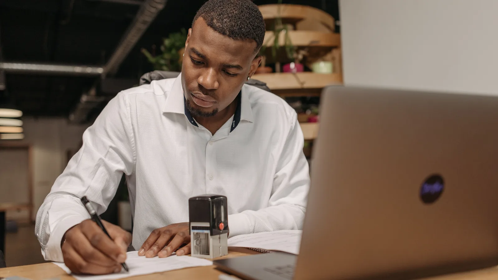 Man completing paperwork beside a laptop