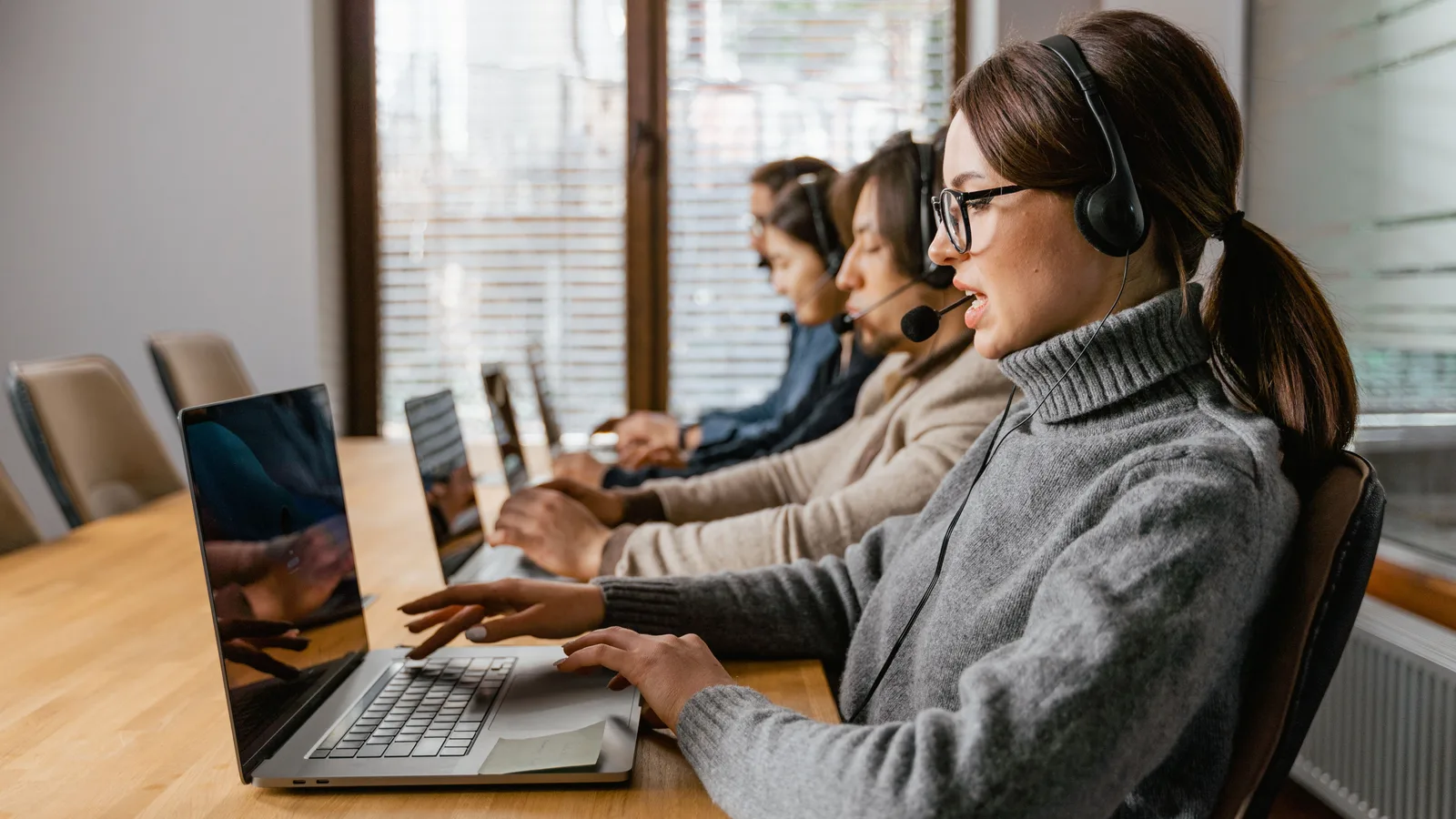 Customer service operators wearing headsets at laptops