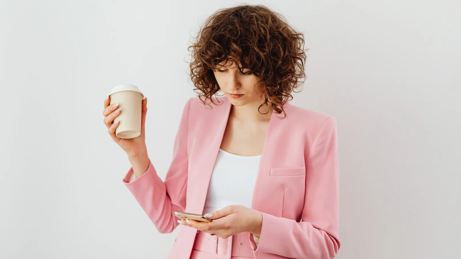 Woman reading her smartphone while holding a cup