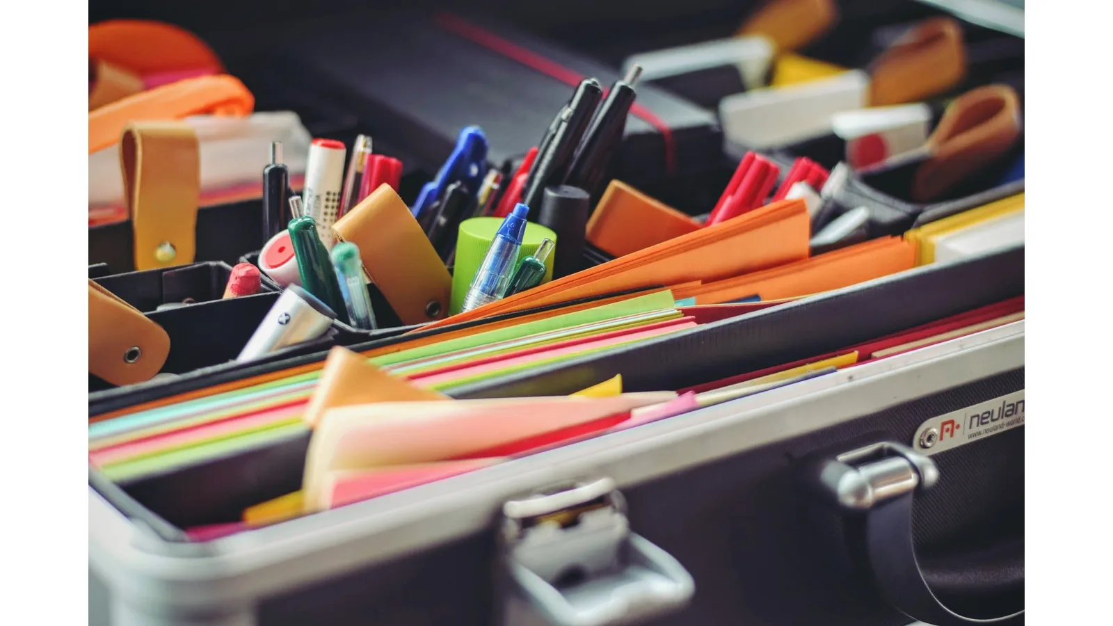 Pens, markers and coloured paper organised in a stationery case