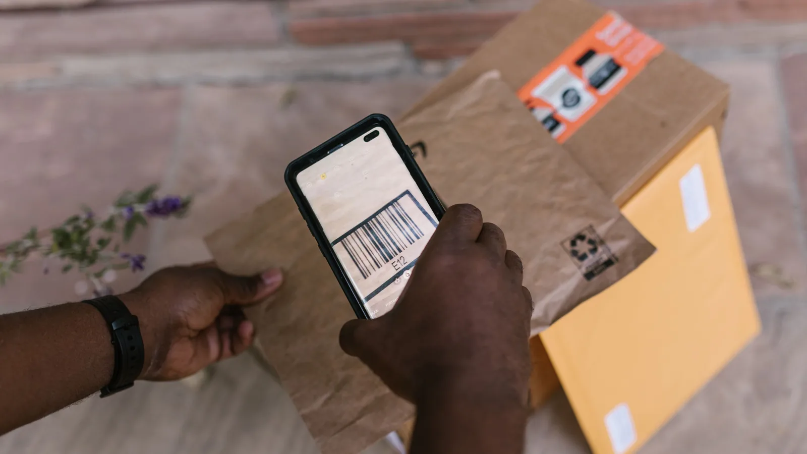 Hands holding a phone camera over a barcode label on a parcel