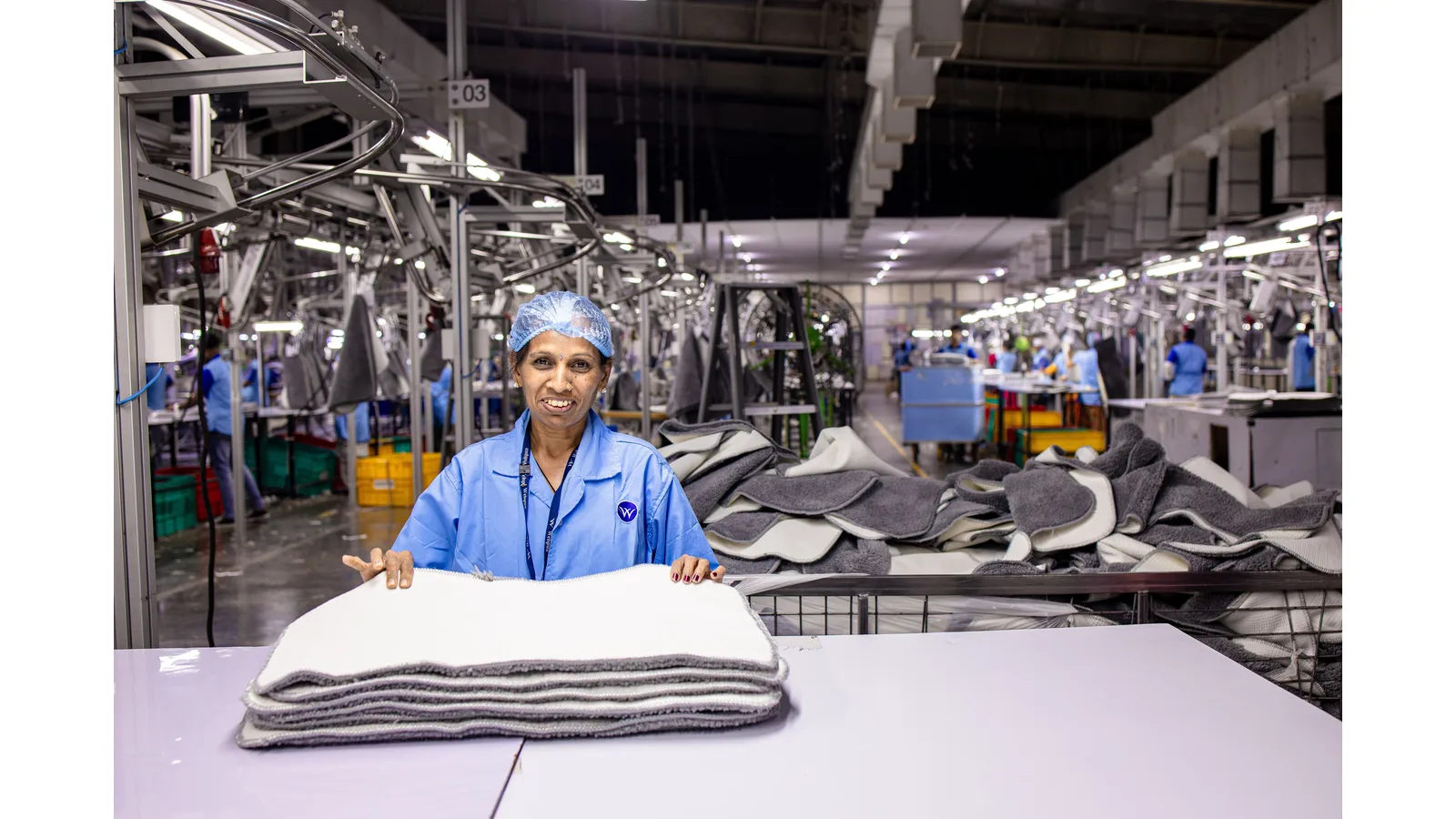 Factory worker handling folded textiles on a production floor