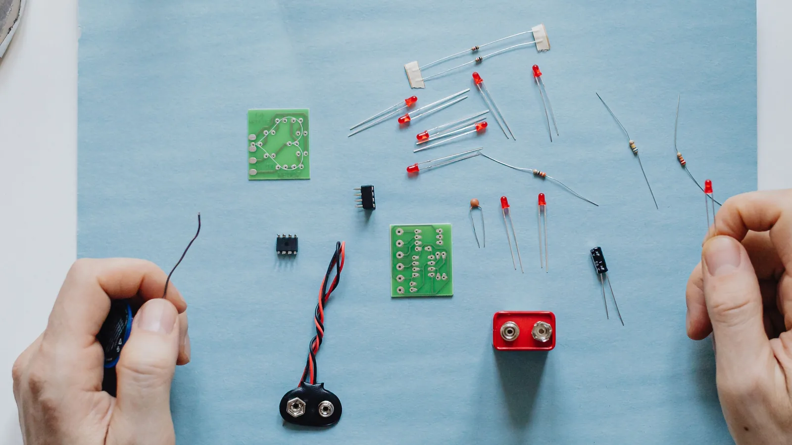Circuit boards, resistors, LEDs and battery connectors laid out between two hands