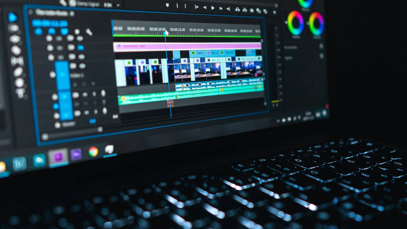 Laptop displaying a video-editing timeline and colour controls