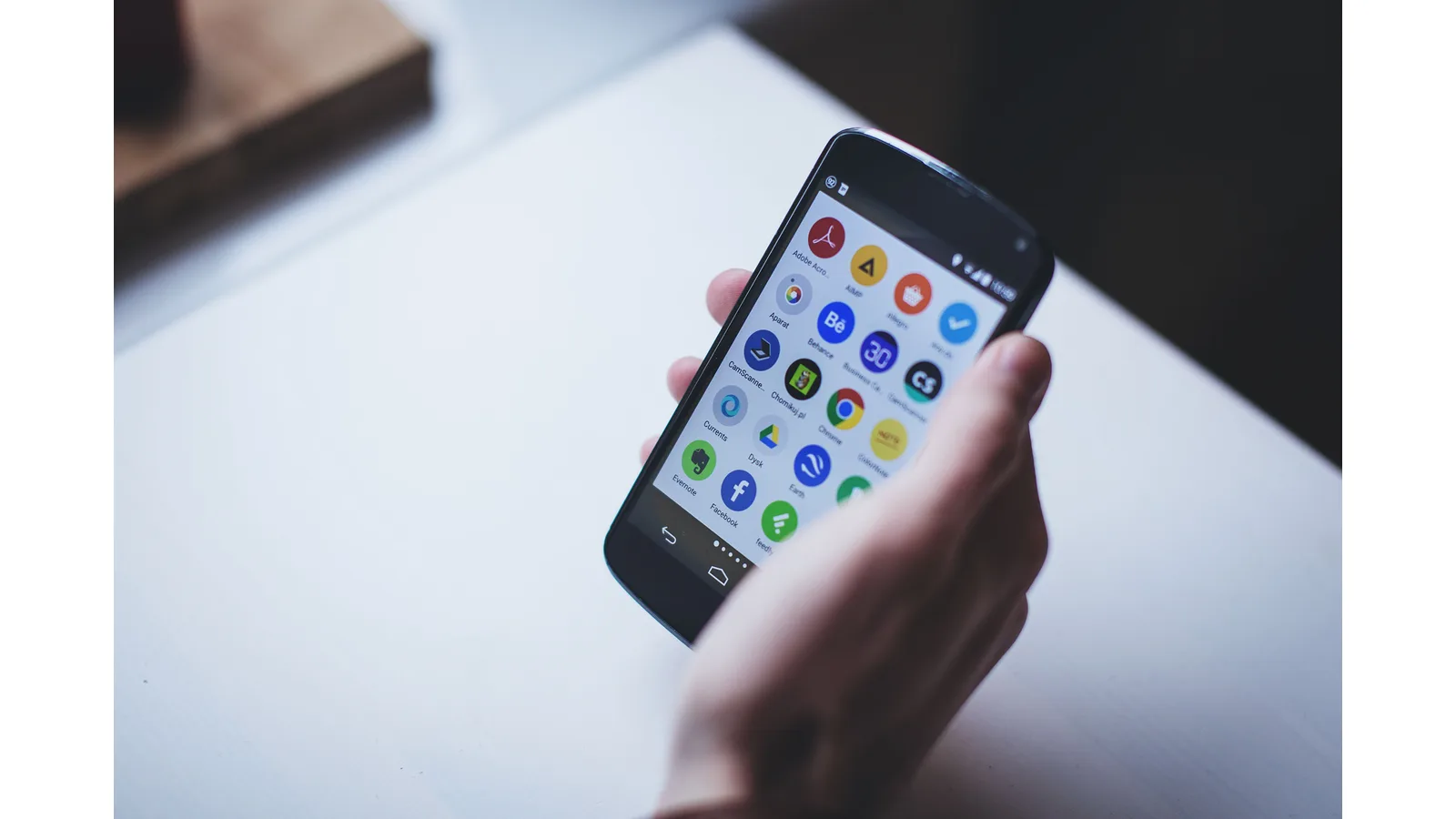 Hand holding a smartphone displaying app icons
