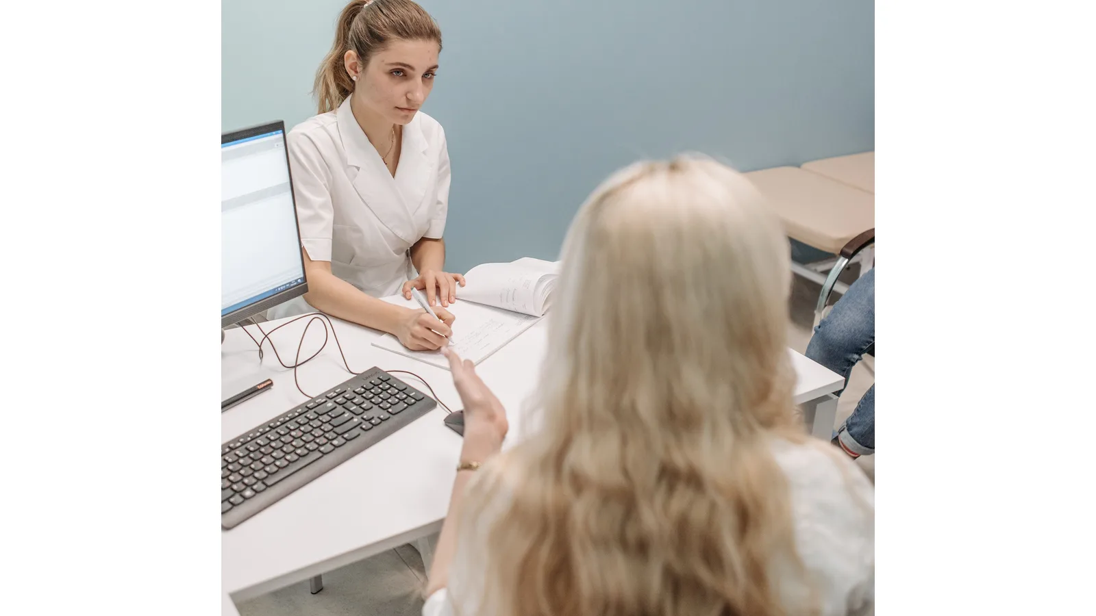 Doctor consulting a patient beside a desktop computer