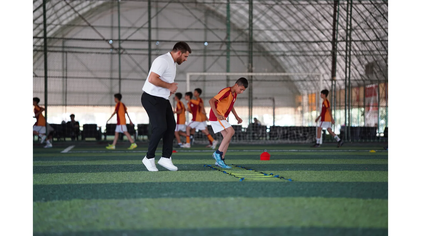 Coach and young player practising beside a training ladder