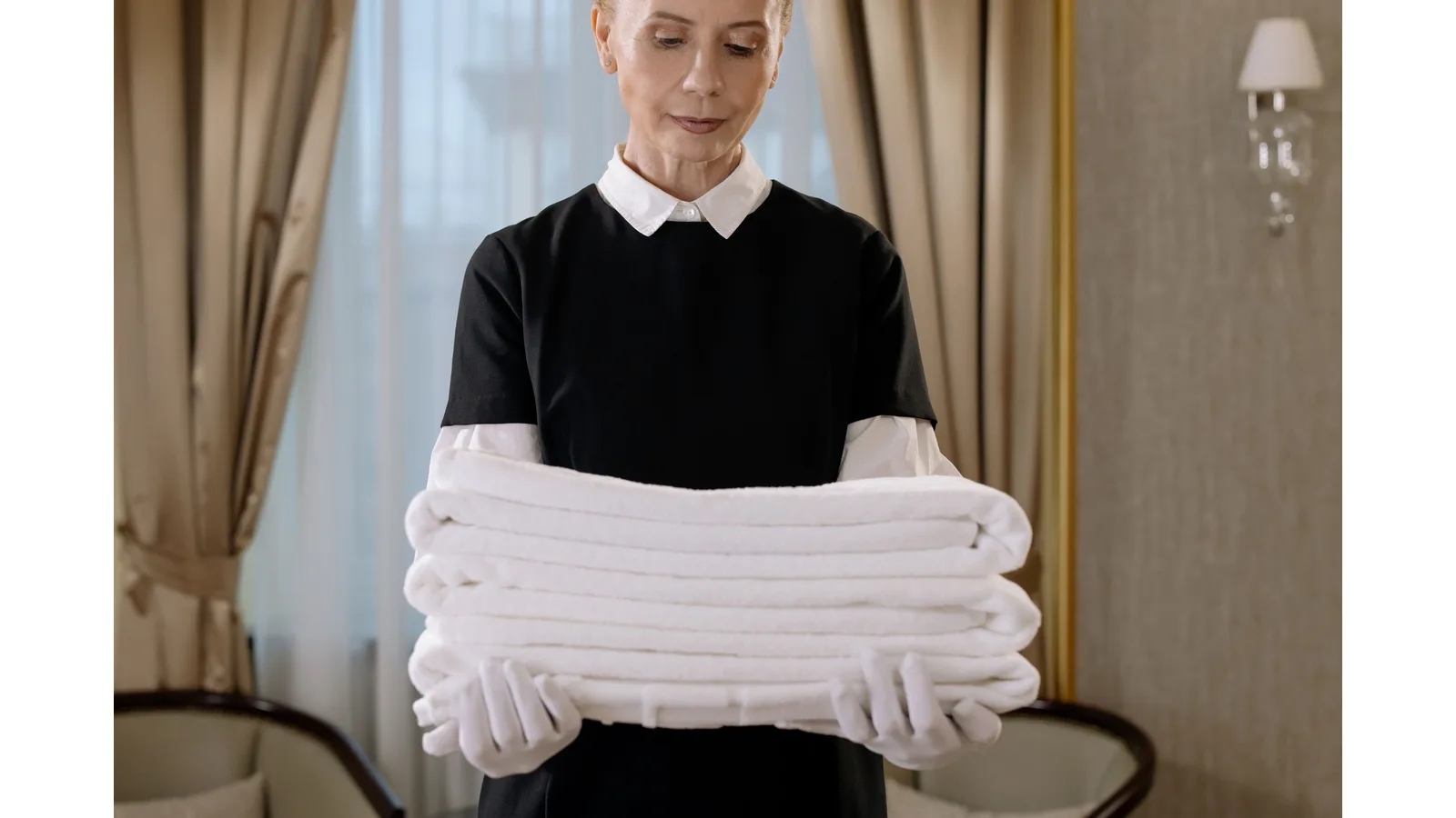 Housekeeper holding a stack of folded white towels