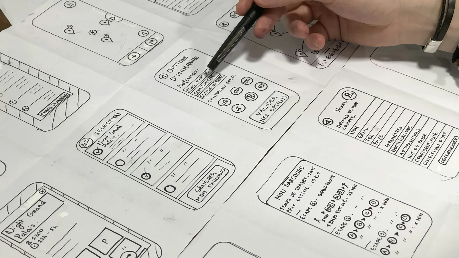 Hand pointing at sketched mobile app screens