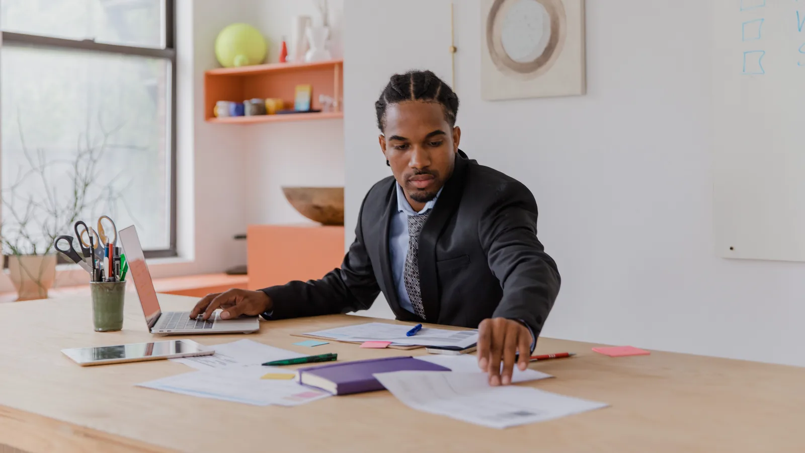 Man arranging business documents beside a laptop