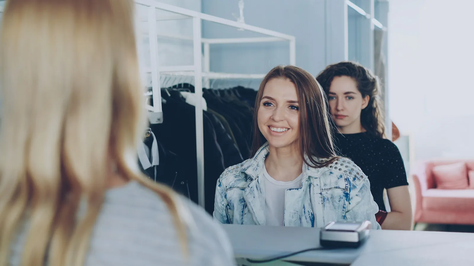 Customers speaking with a shop assistant at a clothing counter