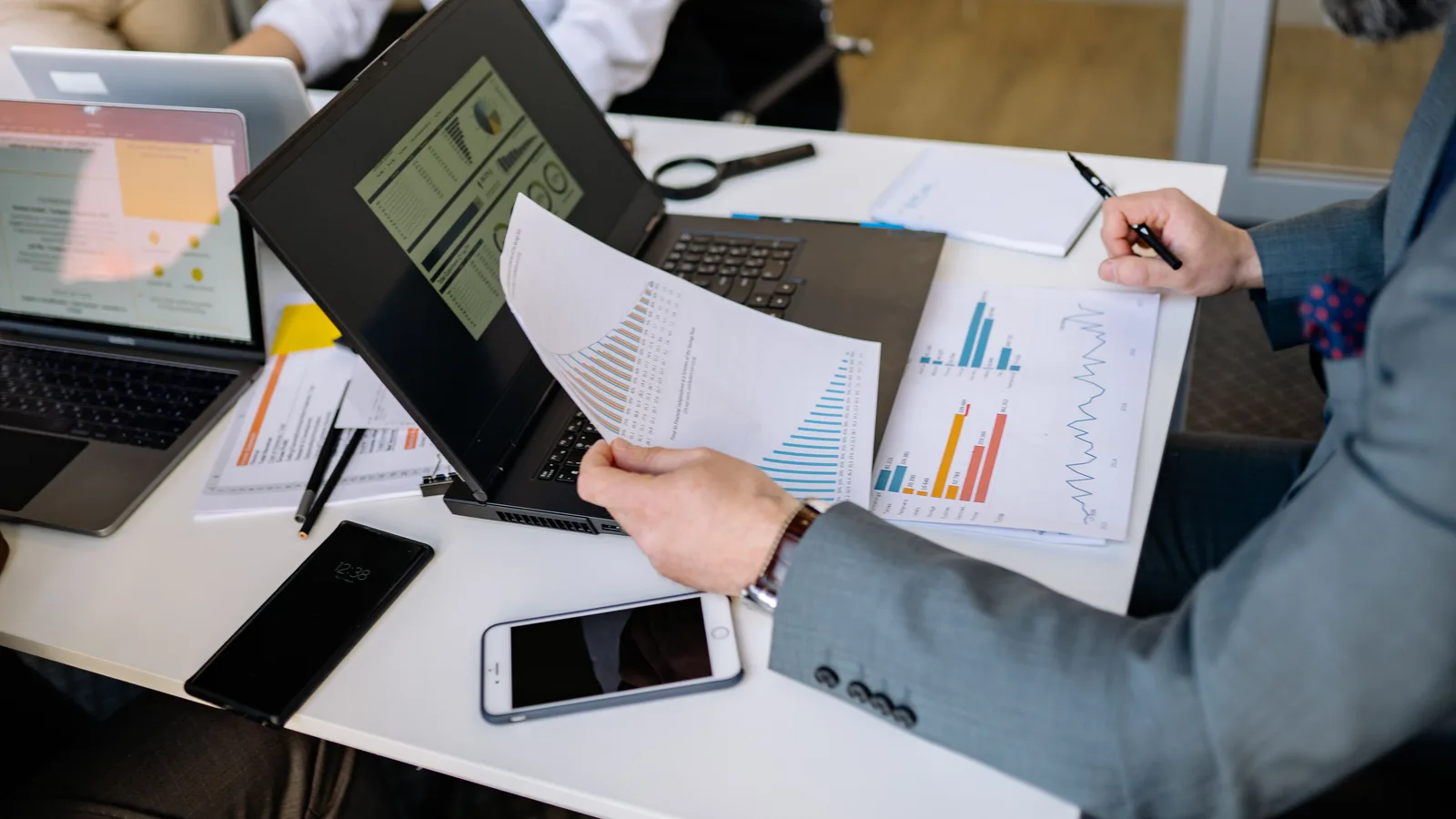 Person comparing printed charts beside a laptop