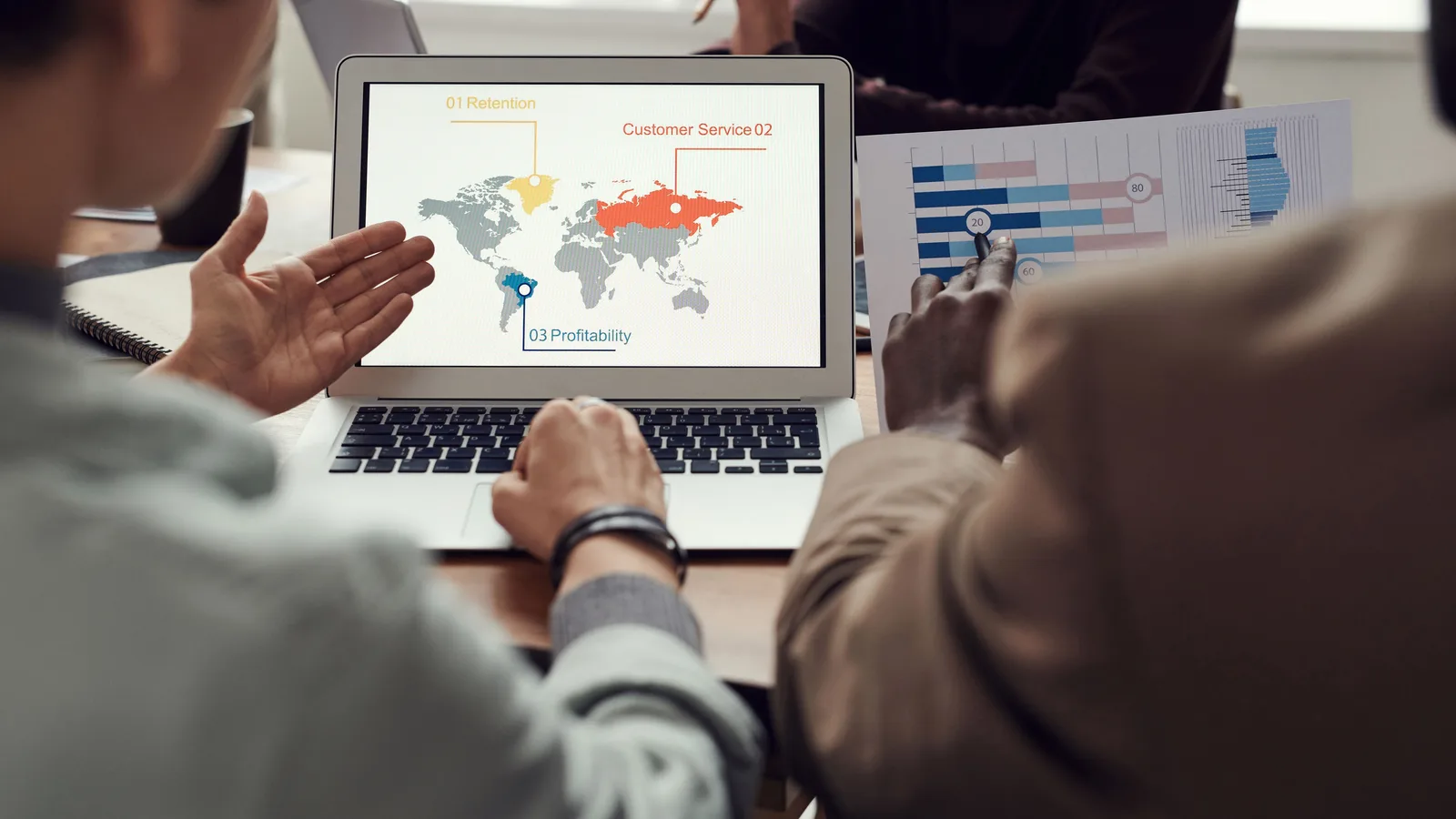 Colleagues discussing a geographic chart on a laptop