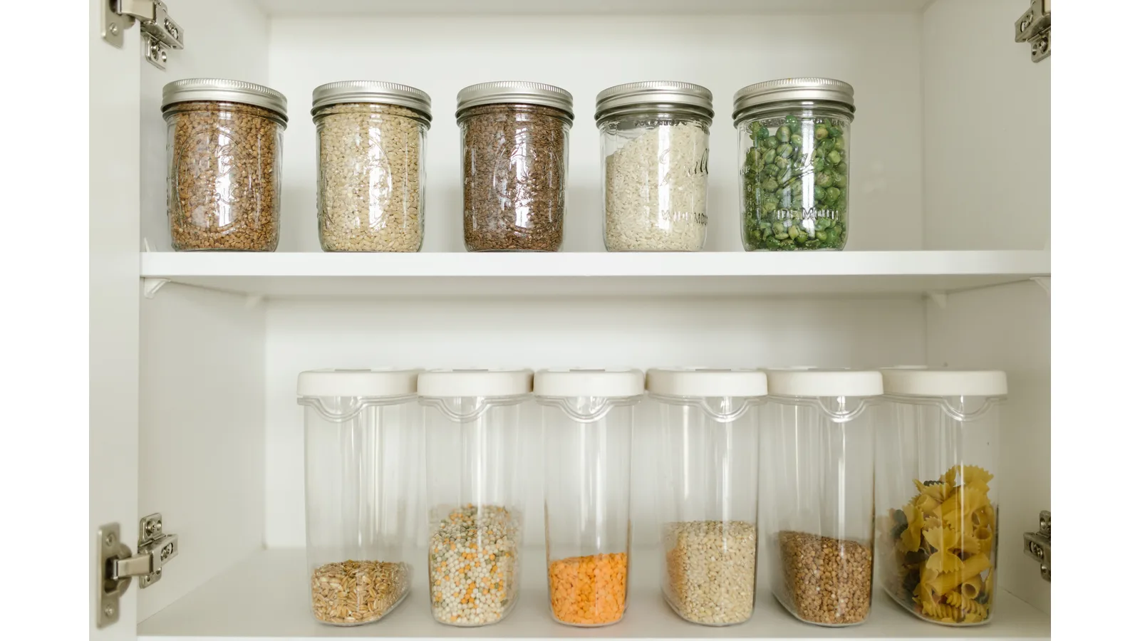 Separate jars of dry food stored on pantry shelves