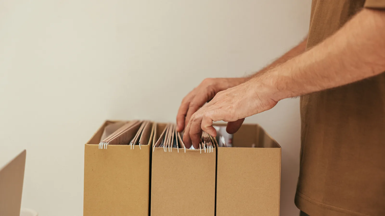 Hands organising hanging folders in archive boxes