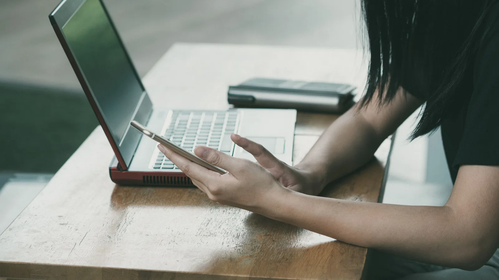 Person using a phone beside a laptop