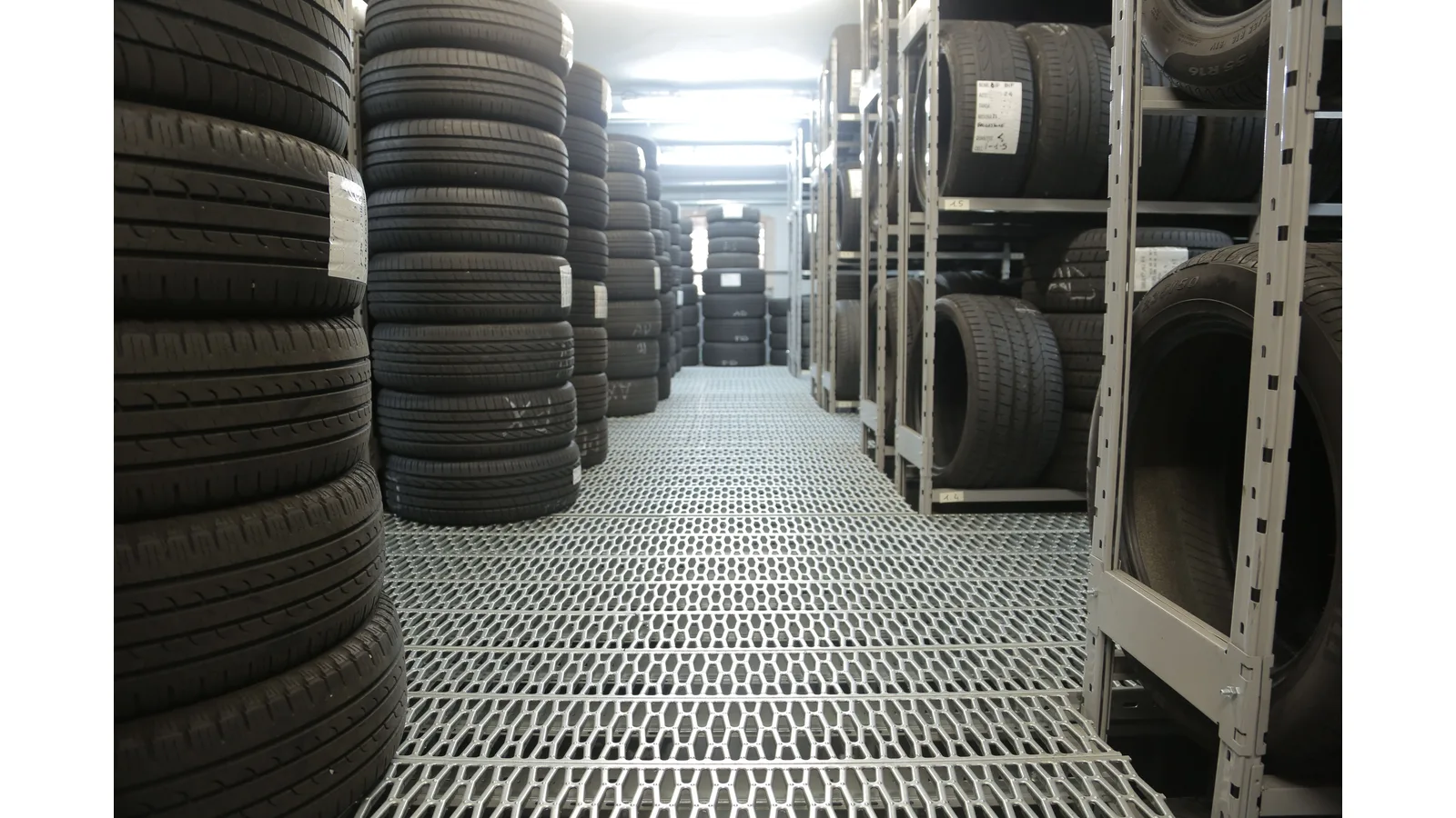 Stacks of tyres on shelves in a storage aisle