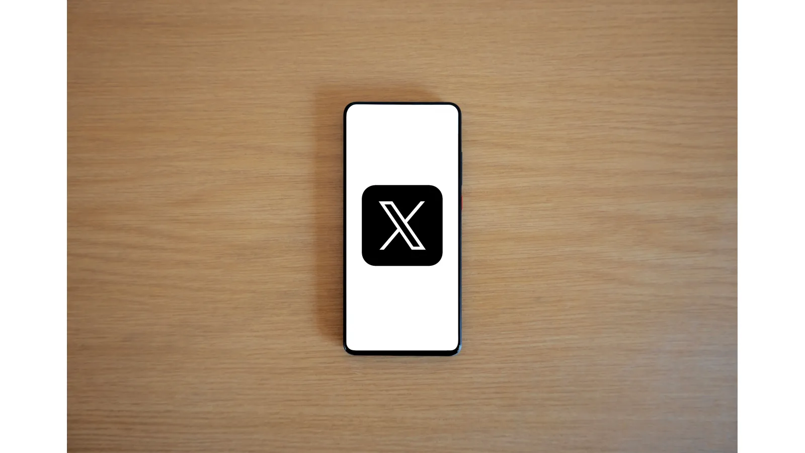 Smartphone displaying an X logo on a white screen