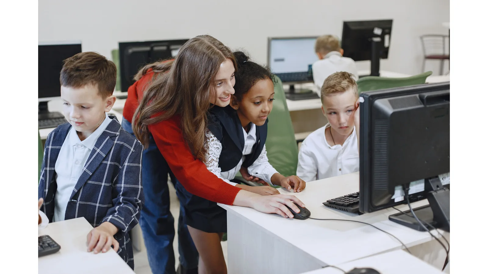 Teacher helping pupils at classroom computers