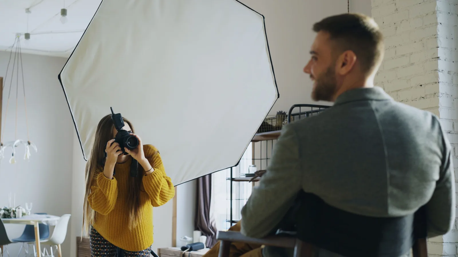 Photographer using a camera in front of a large softbox while photographing a seated man
