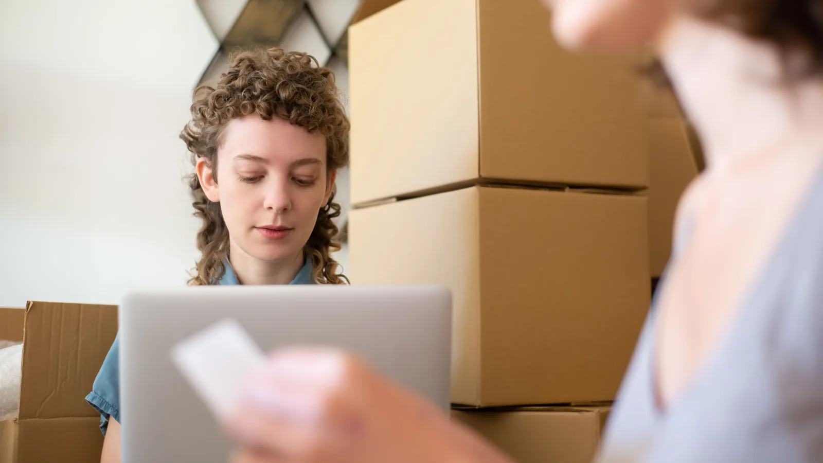 Shop workers using a laptop surrounded by boxes