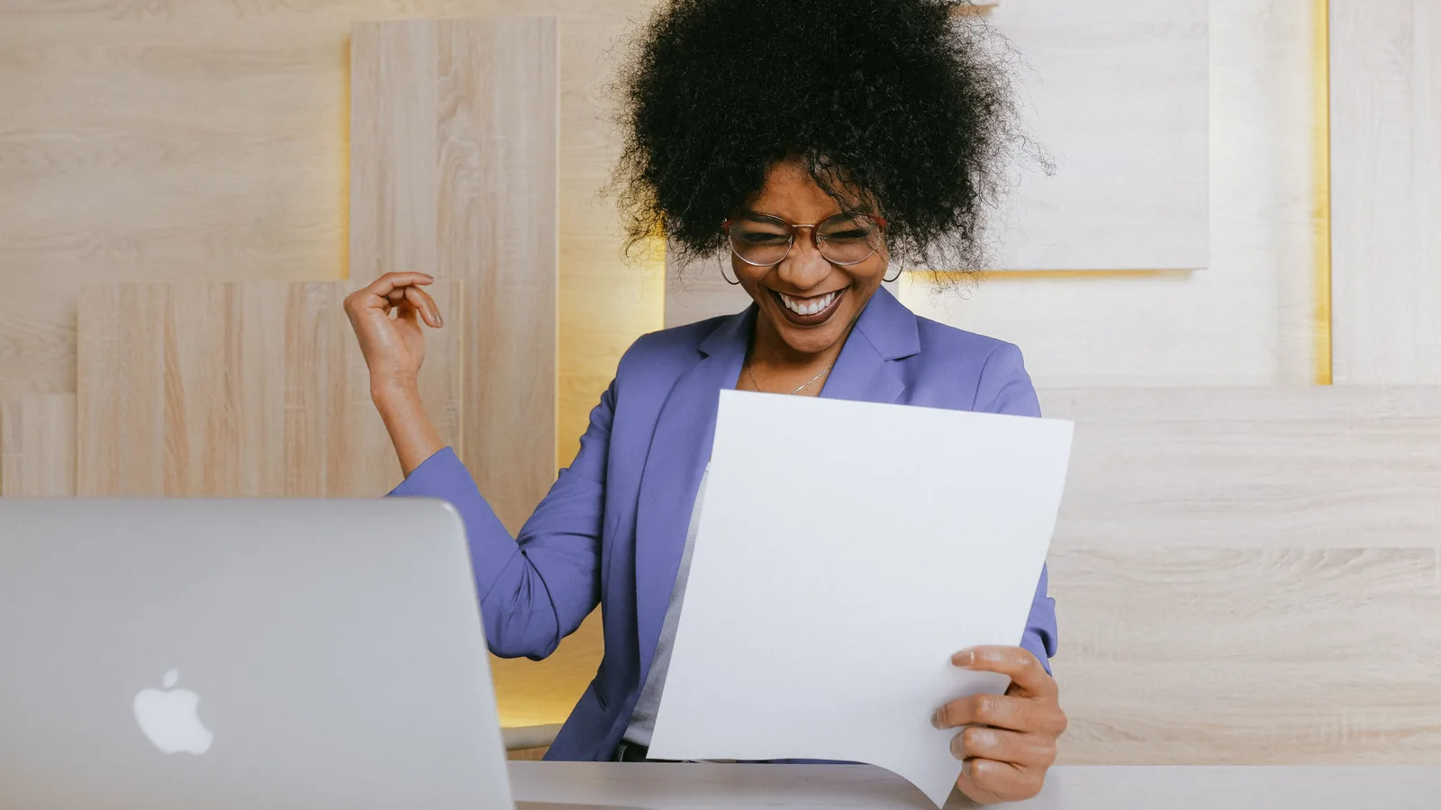 Woman reading a document beside a laptop